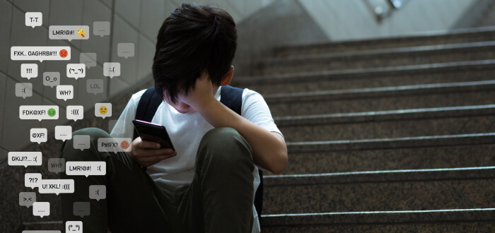 A young boy sits on the stairs, focused on his phone, with a thoughtful expression on his face