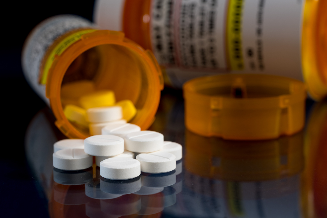 A bottle of pills next to a prescription bottle, illustrating medication and health management