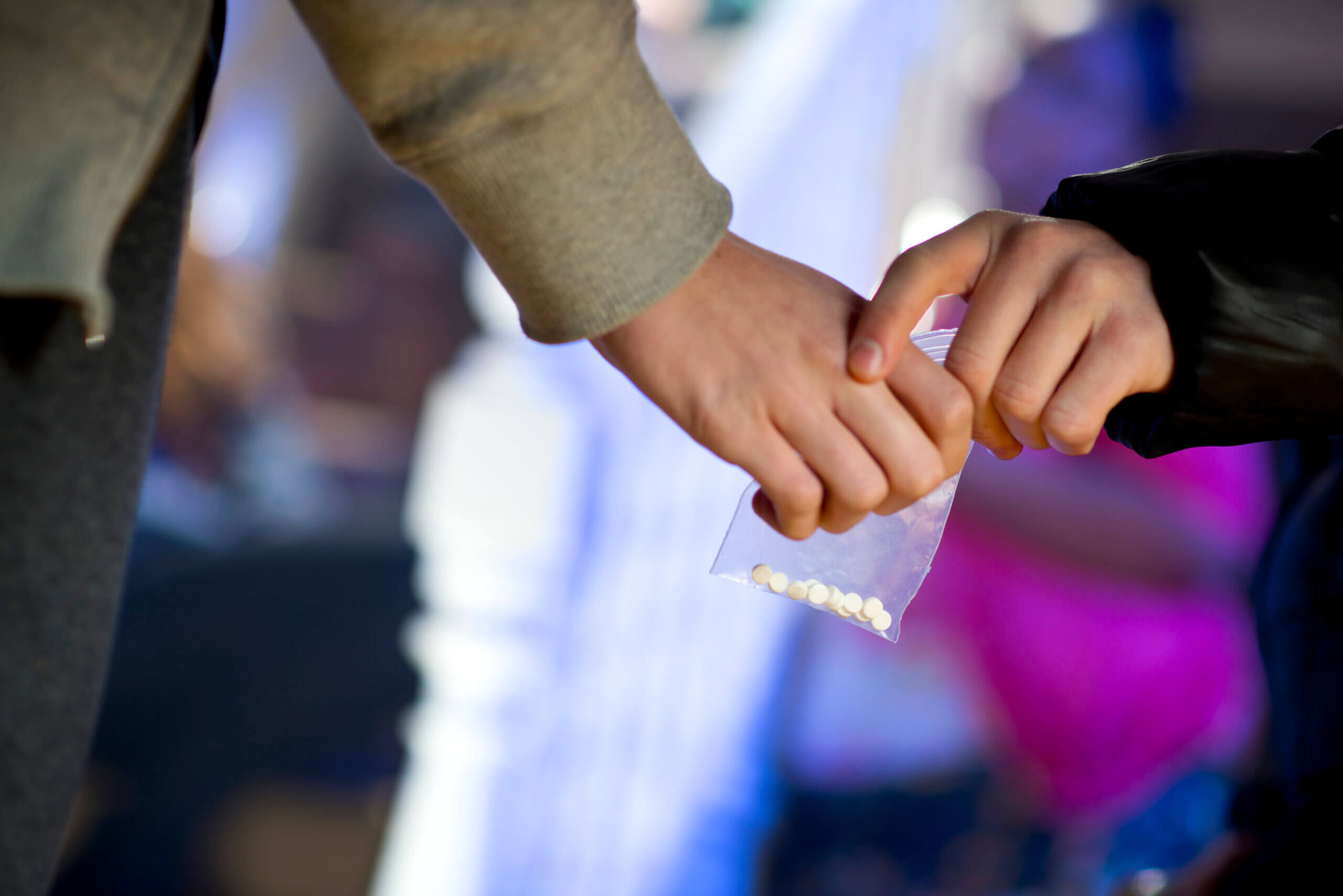 A person holds a bag of pills while another person observes, highlighting a moment of concern or discussion about medication