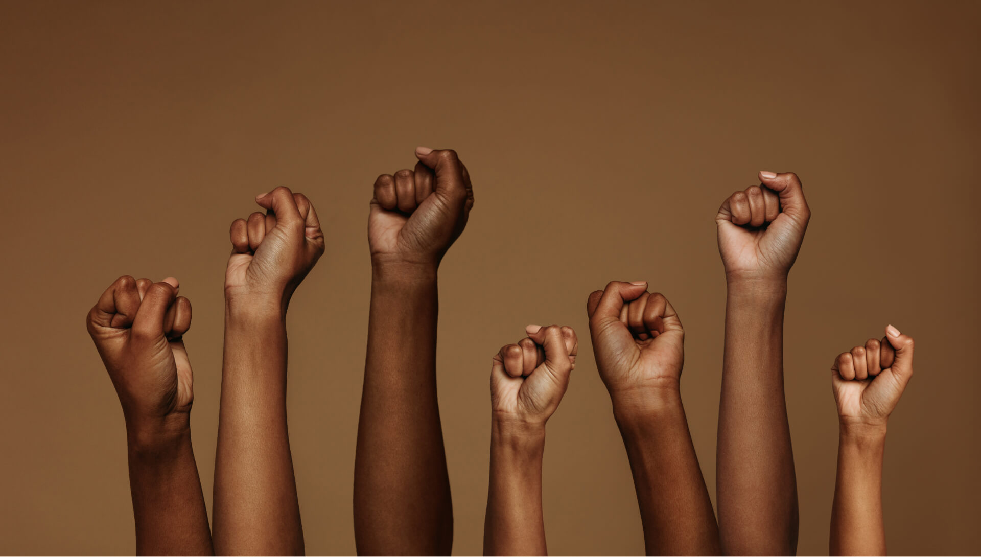 A diverse group of hands raised high, with one hand prominently lifted above the rest, symbolizing unity and enthusiasm