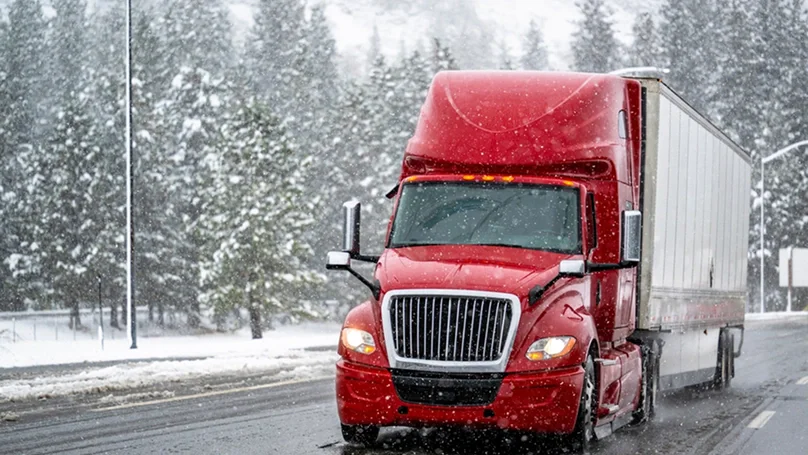 red semi trailer driving on snowy roads