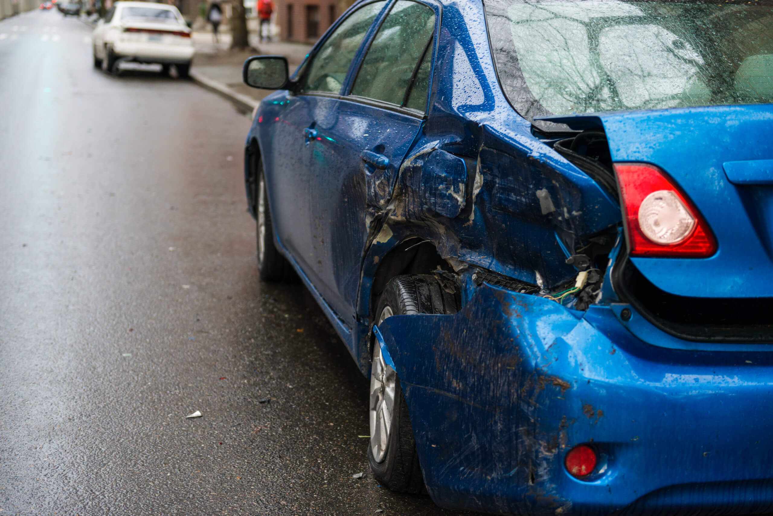 A blue car with visible damage from an accident, showcasing dents and scratches on its exterior