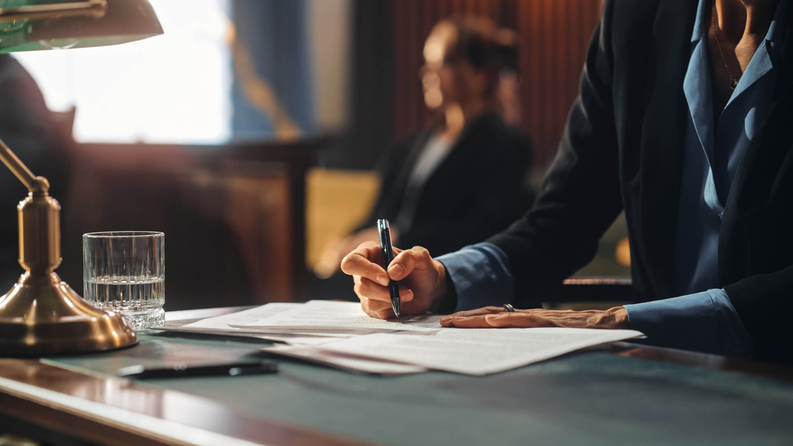 A professional woman in a suit diligently writing on a piece of paper, showcasing focus and determination