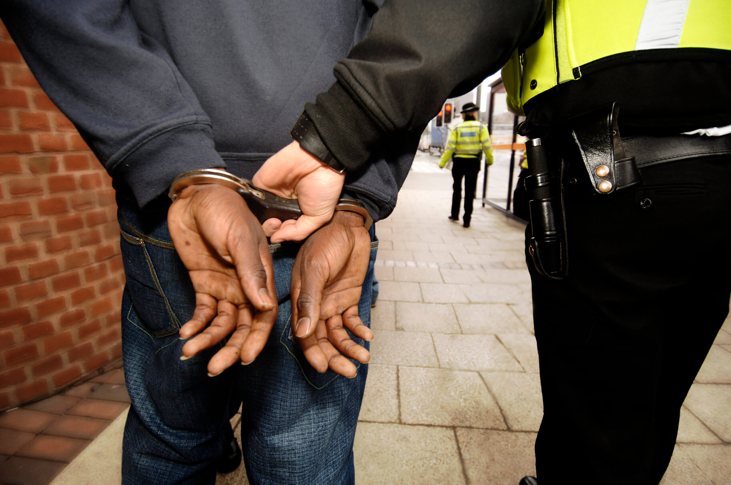 A man in handcuffs is being restrained by another man, indicating a situation of apprehension or arrest