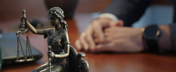 Statue of justice on the table against the background of the hand gestures of a man, a lawyer or a judge